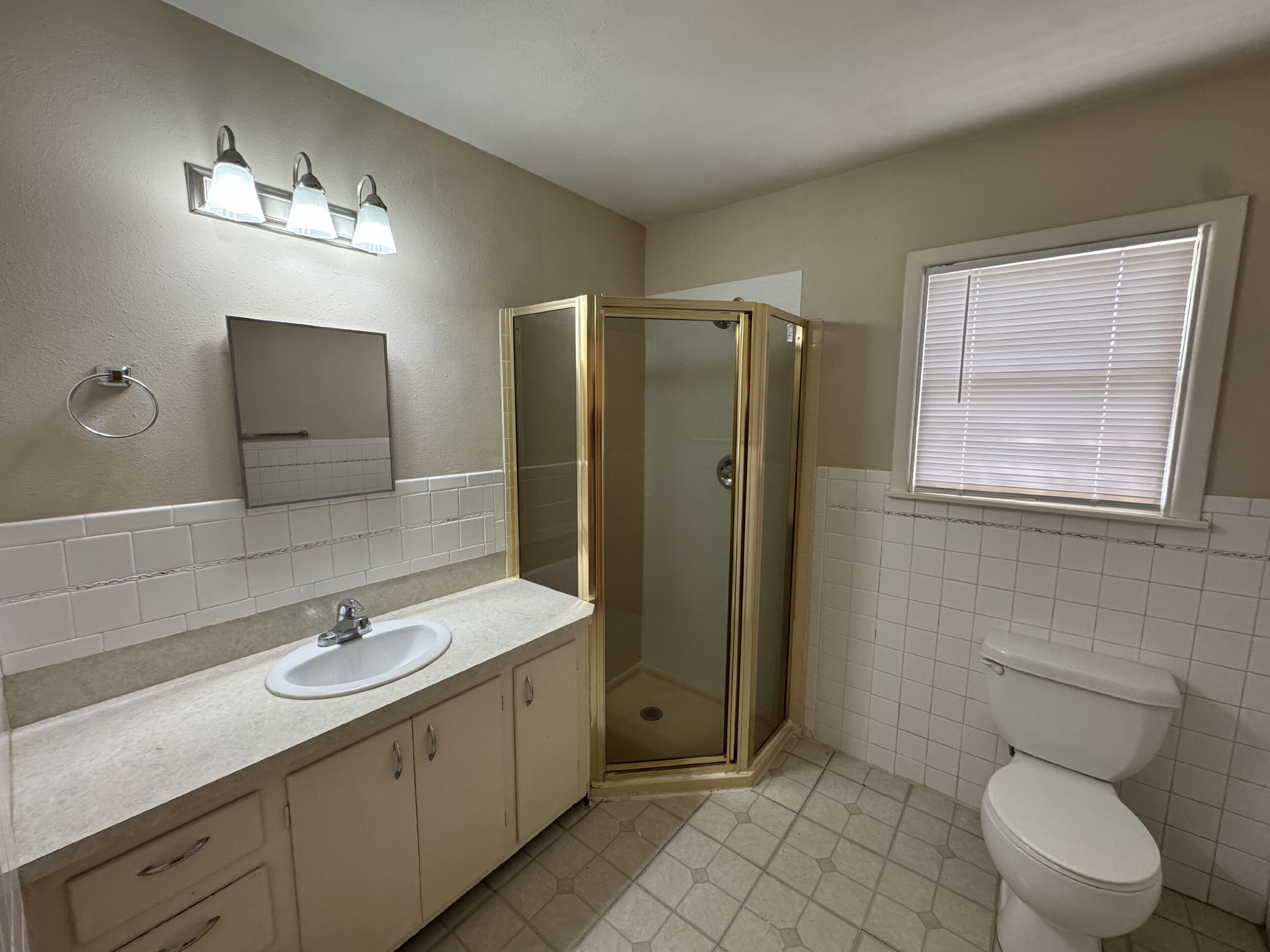 3605 40th Street Lubbock, TX 79413 - Photo 11 of 11 a bathroom with a toilet a sink a mirror and a shower