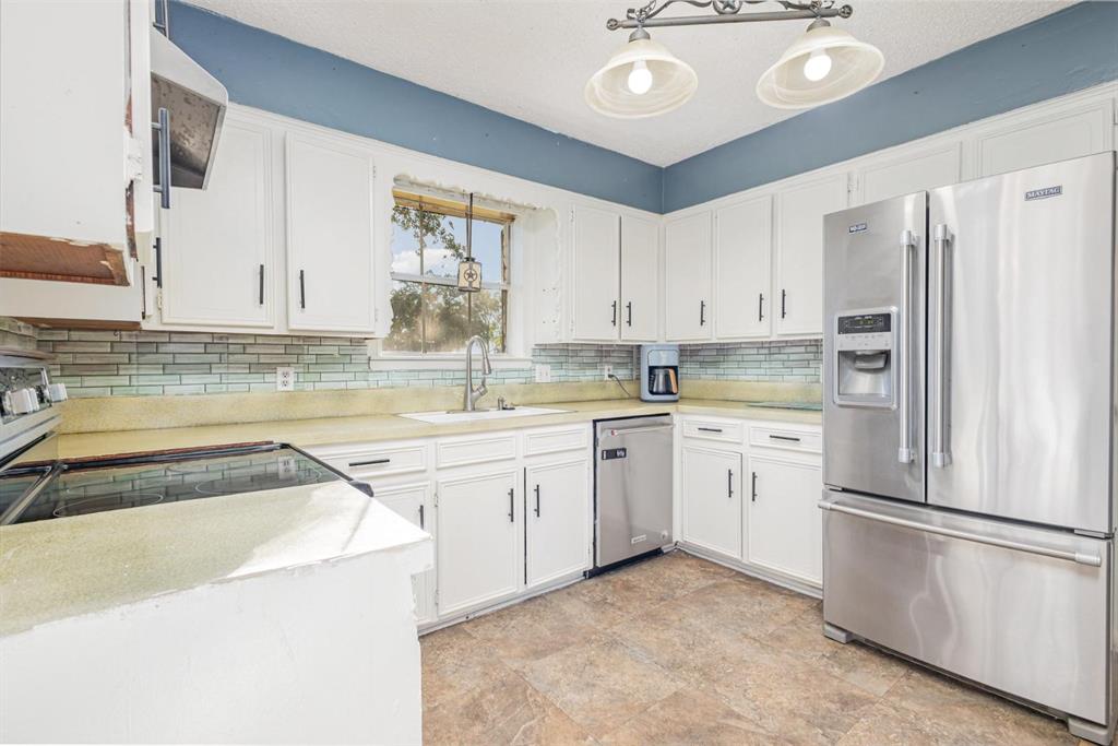 18888 Highway 274 Kemp, TX 75143 - Photo 9 of 30 a kitchen with a refrigerator a stove and white cabinets with wooden floor