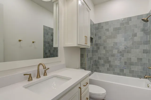 a bathroom with a granite countertop toilet a sink and shower