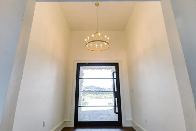 an empty room with wooden floor and a kitchen