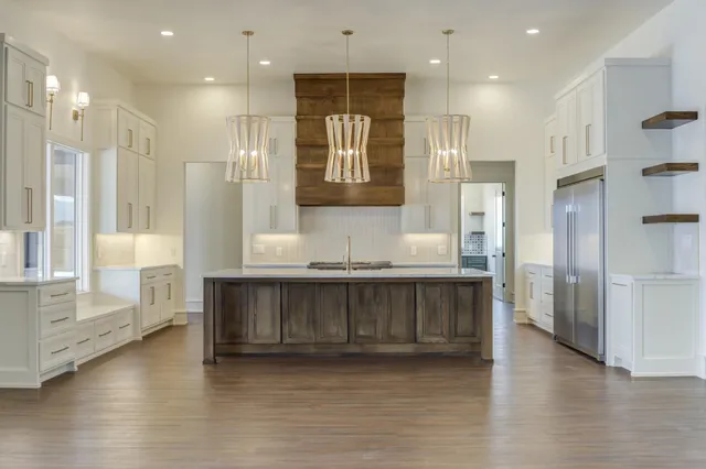 a kitchen with kitchen island granite countertop a sink cabinets and stainless steel appliances