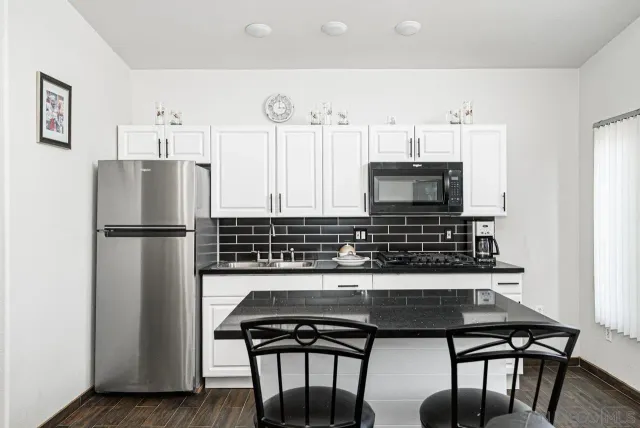 a kitchen with stainless steel appliances a refrigerator a stove a microwave and dining table