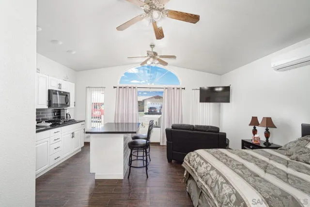 a bedroom with bed a flat tv screen and dresser