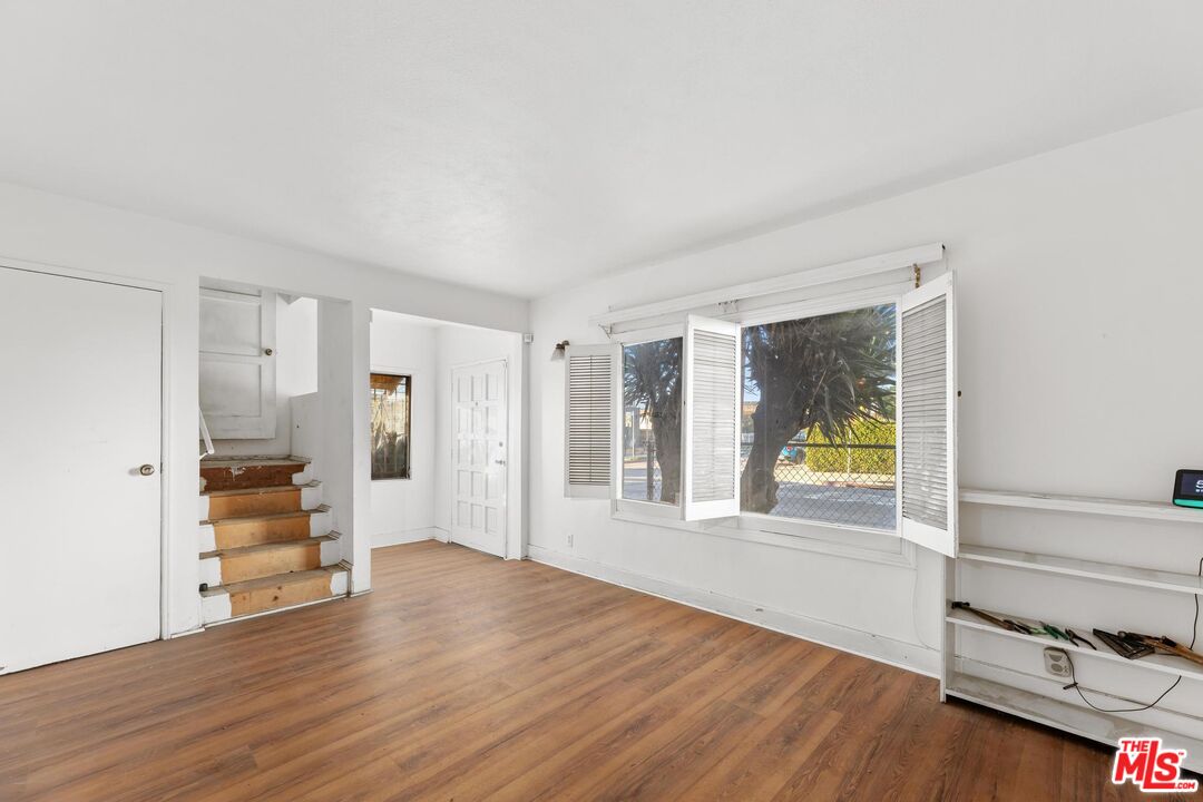 1650 South Rimpau Boulevard Los Angeles, CA 90019 - Photo 5 of 52 a view of an empty room and a kitchen with wooden floor