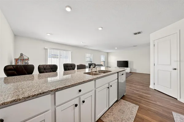 a kitchen with granite countertop a sink and white cabinets with wooden floor