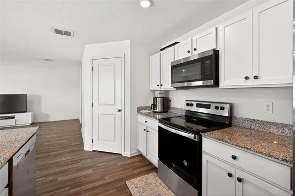 a kitchen with granite countertop a stove and a microwave