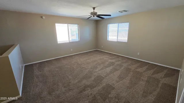 an empty room with windows and fan