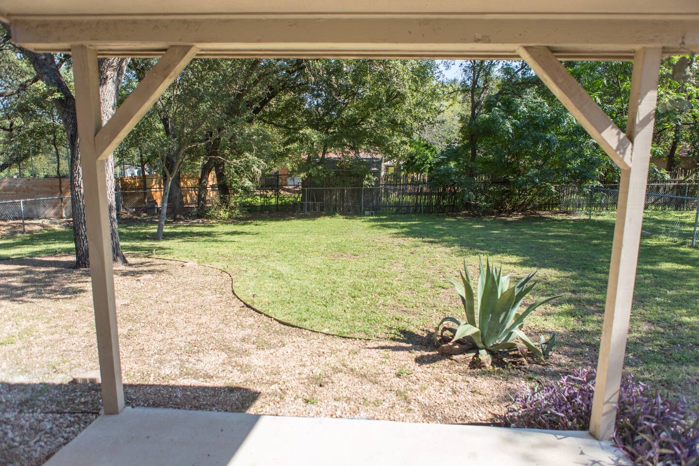 1913 Rabb Road, Unit B Austin, TX 78704 - Photo 10 of 10 A spacious yard extends beyond the covered patio, framed by mature trees and verdant landscaping.