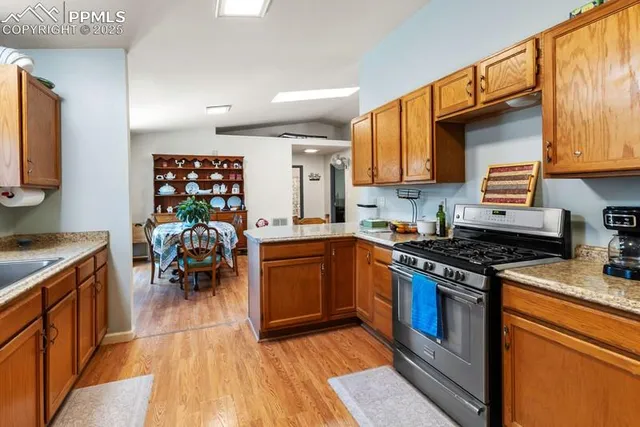 a kitchen with stainless steel appliances granite countertop a stove top oven a sink and a refrigerator