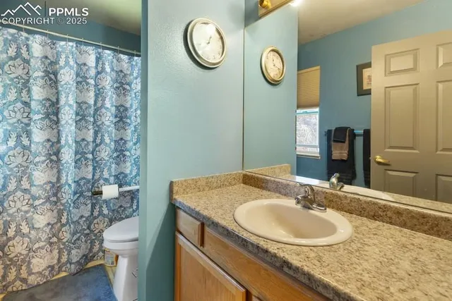 a bathroom with a granite countertop sink a toilet and a mirror