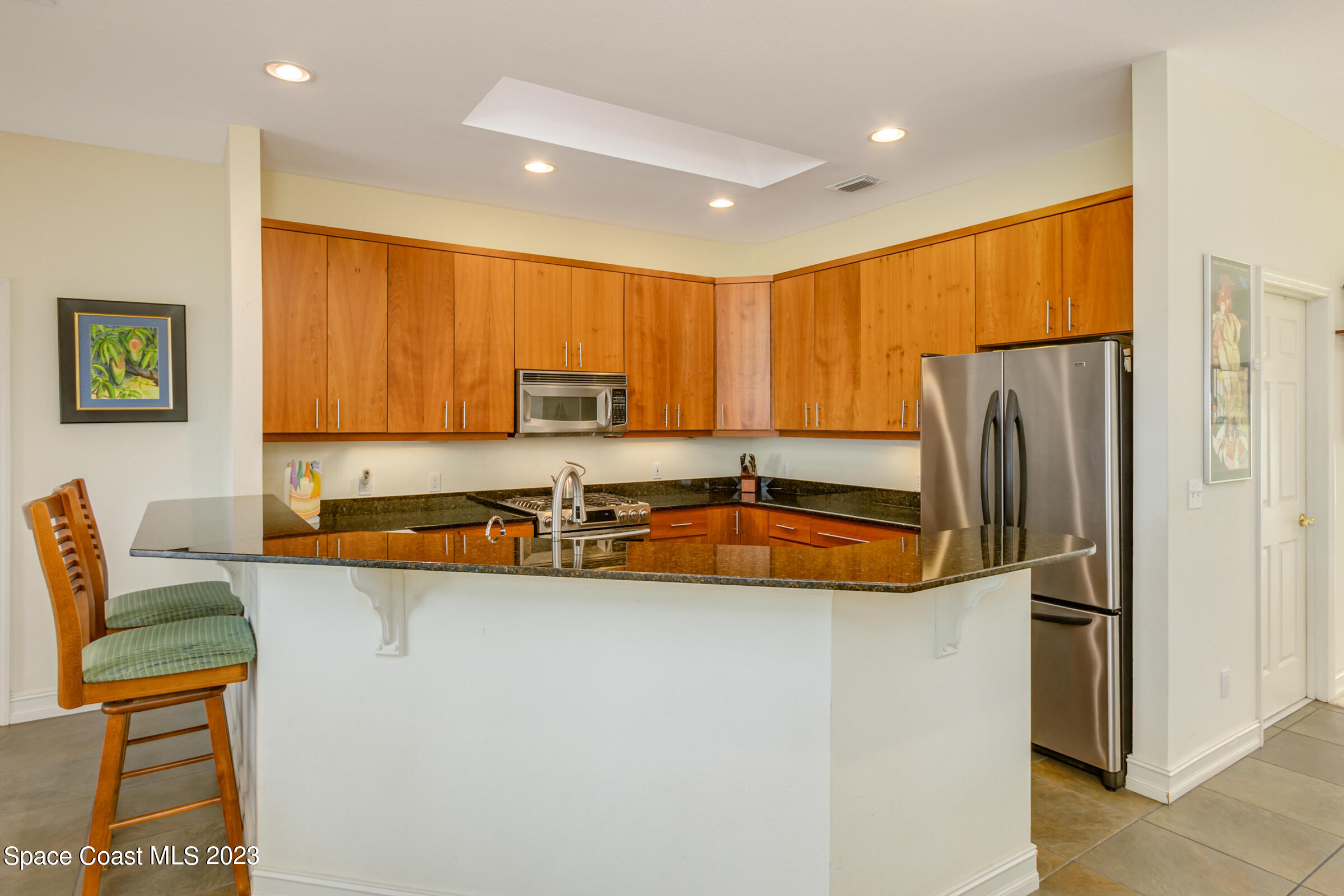 4553 Coquina Ridge Drive Melbourne, FL 32935 - Photo 19 of 51 a kitchen with stainless steel appliances granite countertop a refrigerator a sink a stove a dining table and chairs with wooden floor