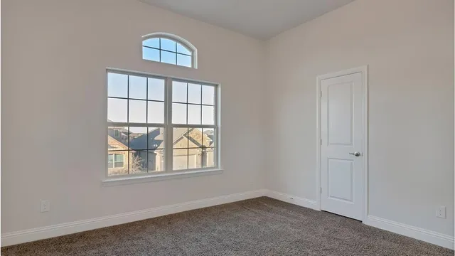an empty room with windows and chandelier fan