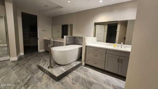 a spacious bathroom with a double vanity sink a mirror and a bathtub