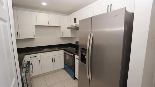 a kitchen with a refrigerator and white cabinets