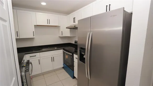 a kitchen with a refrigerator and white cabinets