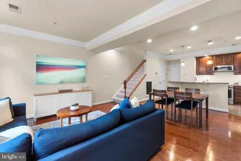 a living room with furniture kitchen view and a wooden floor