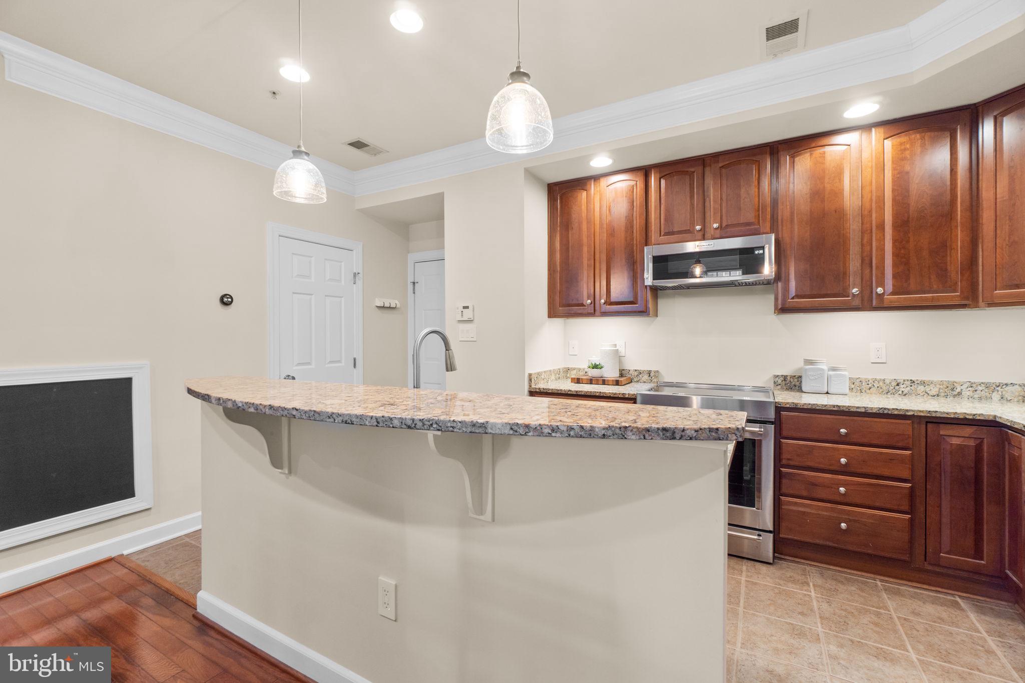 9504 Hyde Place Frederick, MD 21704 - Photo 9 of 43 a kitchen with stainless steel appliances granite countertop a sink a stove and a microwave