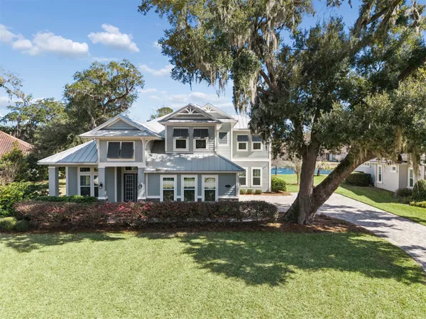 a front view of a house with a garden and trees