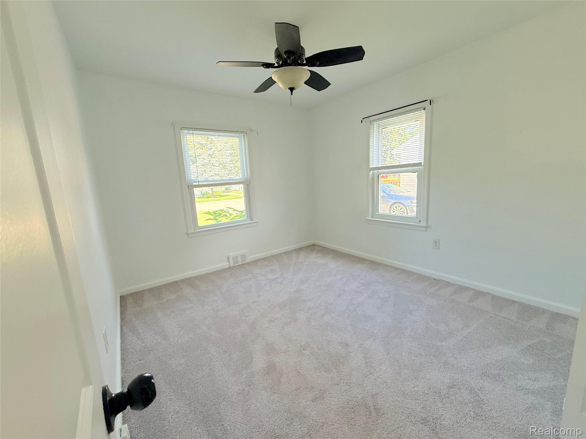 21212 Rensselaer Street Farmington, MI 48336 - Photo 7 of 11 Bright interior featuring two windows, neutral carpeting, a ceiling fan with integrated lighting, white walls, and white trim