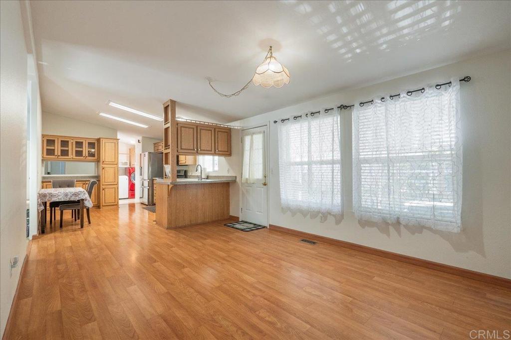 13941 Wisteria Avenue, Unit 53 Poway, CA 92064 - Photo 18 of 28 a living room with stainless steel appliances kitchen island granite countertop a stove a refrigerator a sink a dining table and chairs with wooden floor