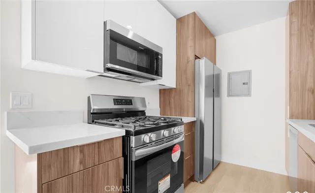 a kitchen with stainless steel appliances a sink a stove a microwave a refrigerator and cabinets