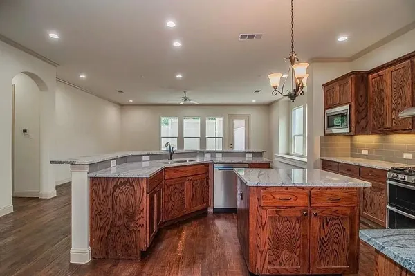 a large kitchen with stainless steel appliances granite countertop a sink a stove and a wooden floors