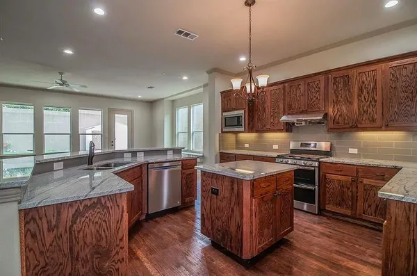 a kitchen with stainless steel appliances granite countertop a stove a sink dishwasher a refrigerator and a oven with wooden floor