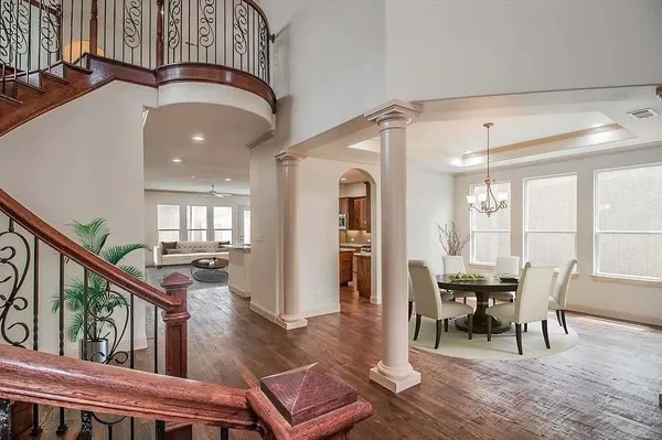 a dining room with wooden floor a chandelier a wooden table and chairs