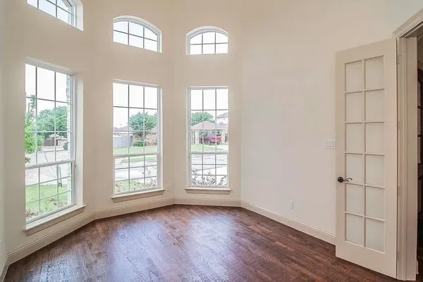 an empty room with wooden floor closet and windows
