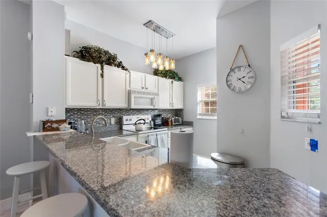 a kitchen with granite countertop a sink cabinets and stainless steel appliances