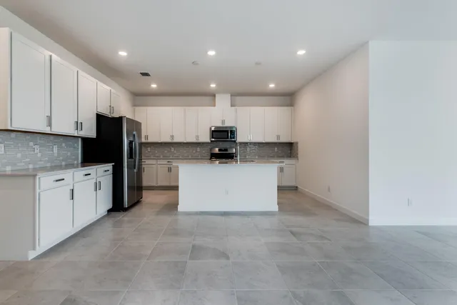 a kitchen with stainless steel appliances granite countertop a stove top oven a sink and white cabinets