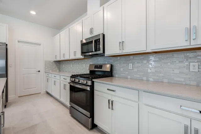 a kitchen with white cabinets and stainless steel appliances