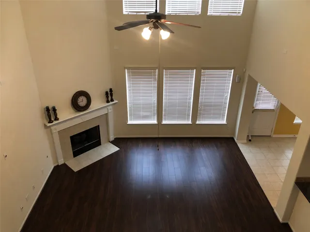 a view of an empty room with wooden floor and windows