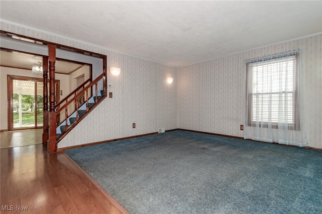5223 Edenhurst Road Cleveland, OH 44124 - Photo 4 of 50 Unfurnished room featuring crown molding, stairway, a chandelier, wood finished floors, and a textured ceiling