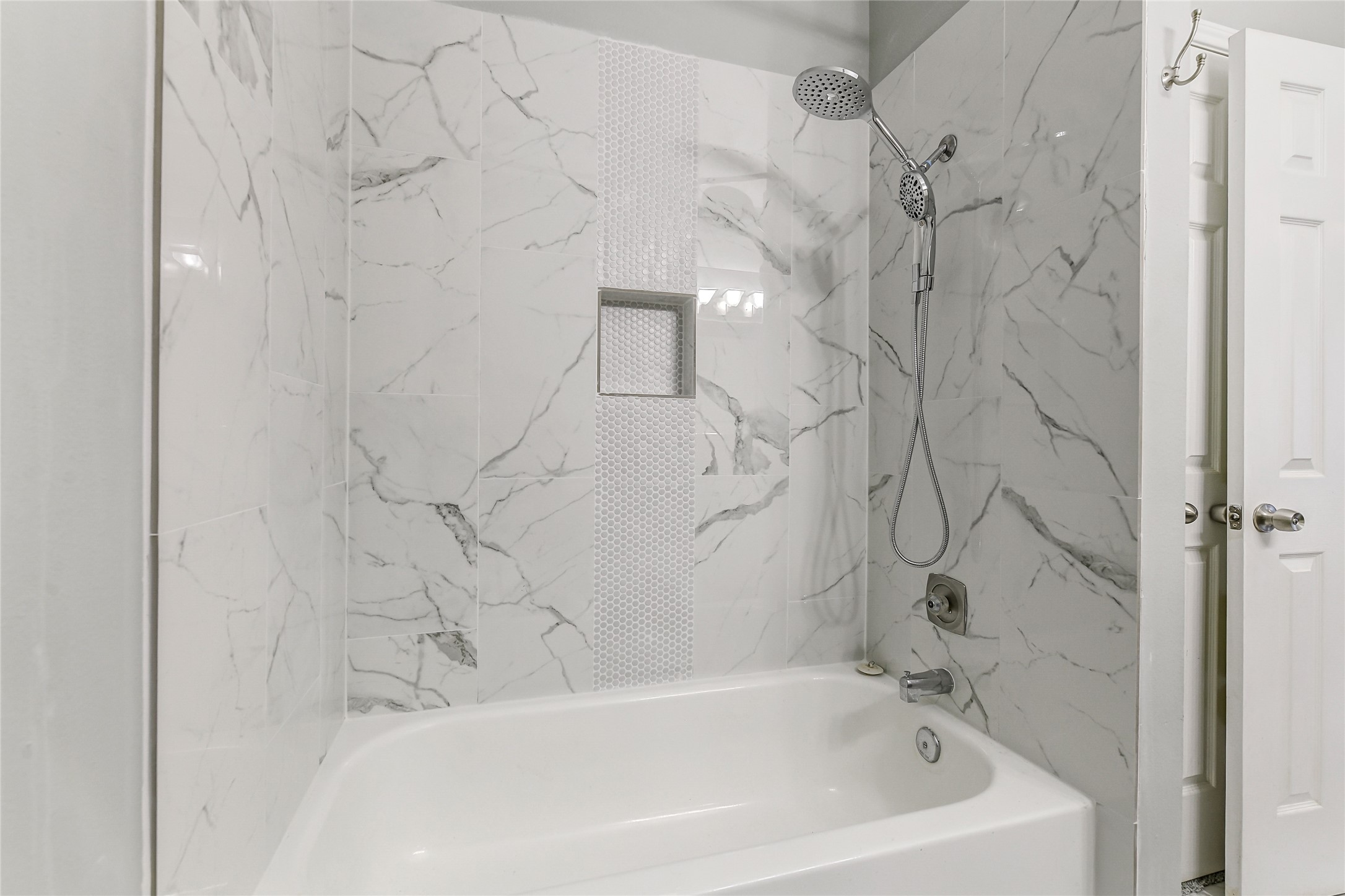 4001 Tanglewilde Street, Unit 1402 Houston, TX 77063 - Photo 19 of 23 Discover a sophisticated tub/shower combo with updated fixtures and a sleek surround, featuring a convenient inset for products, plus a handy storage closet tucked behind the bathroom door.