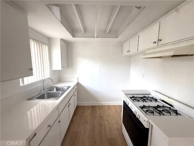 a kitchen with white cabinets stove and sink
