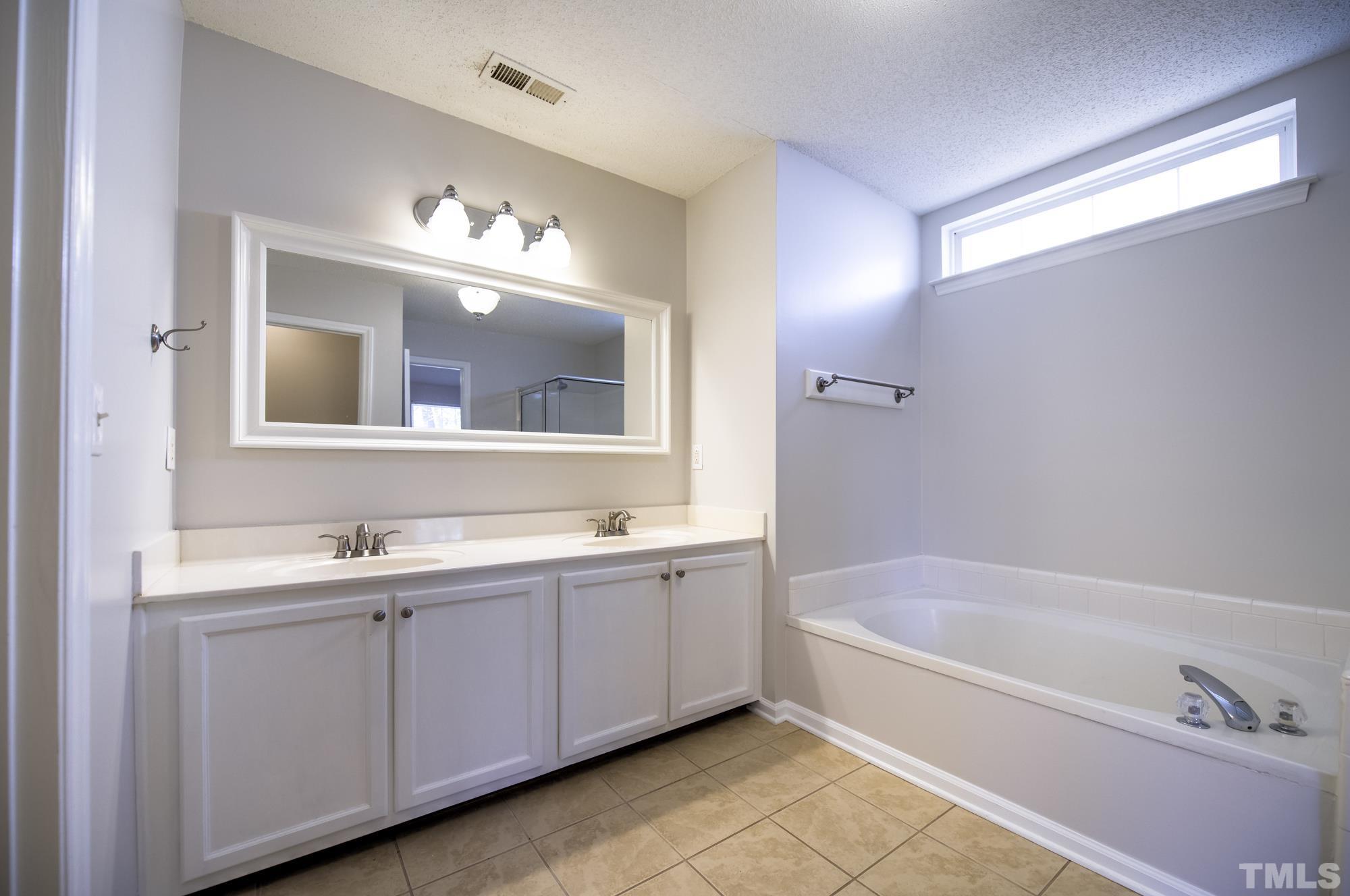 6809 Edwell Court Raleigh, NC 27617 - Photo 14 of 26 a bathroom with a tub a sink and mirror