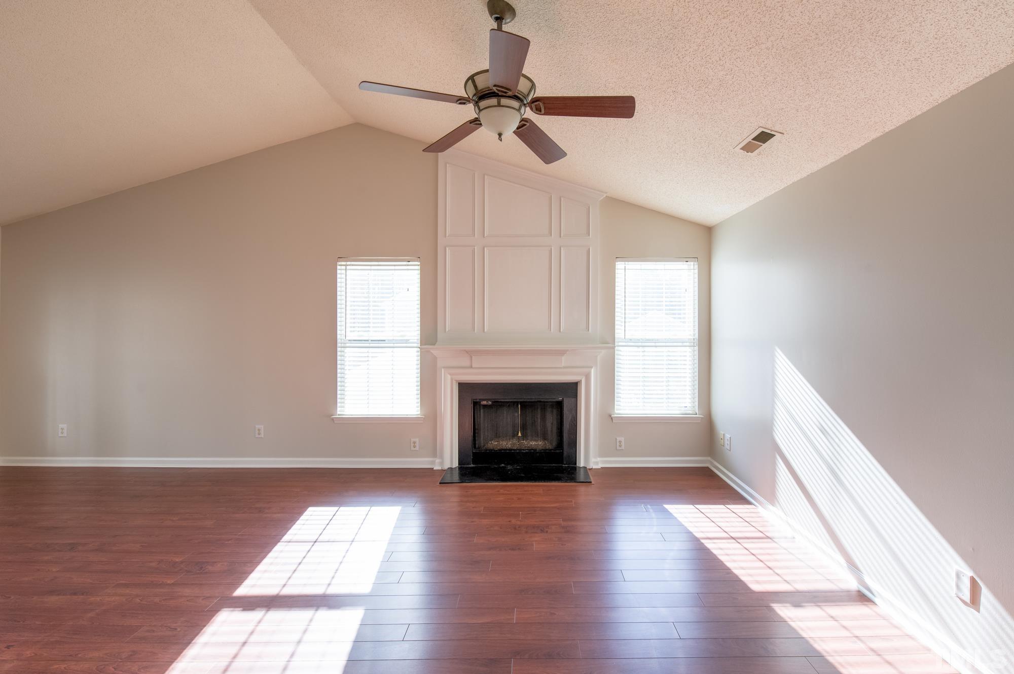 6809 Edwell Court Raleigh, NC 27617 - Photo 4 of 26 a view of a livingroom with a fireplace a ceiling fan and windows
