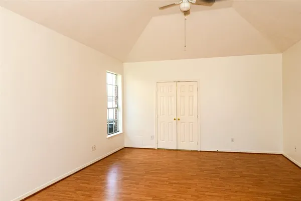 a view of empty room with wooden floor and fan