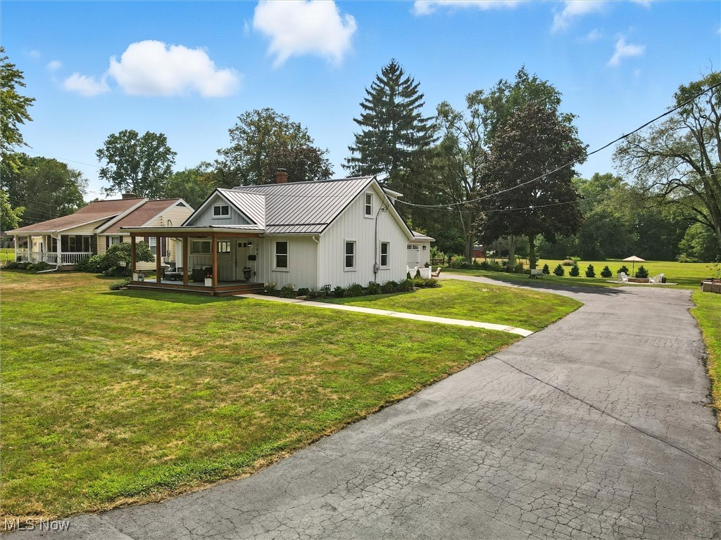 194 Ansel Road Geneva, OH 44041 - Photo 2 of 41 View of front of property with a metal roof, a standing seam roof, a porch, driveway, and a front yard
