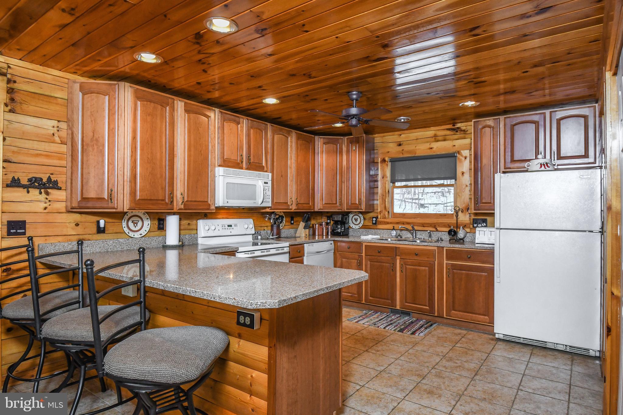 412 Tanglewood Road Oakland, MD 21550 - Photo 12 of 41 a kitchen with stainless steel appliances granite countertop a stove a refrigerator a sink a dining table and chairs with the cabinets