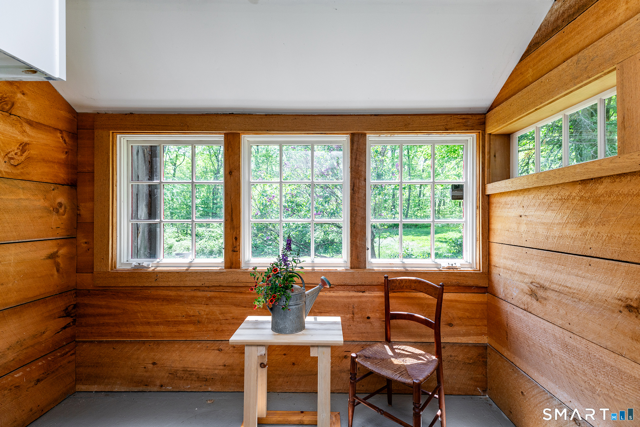 25 Bald Hill Road Kent, CT 06785 - Photo 10 of 38 Sunlight floods this cozy breakfast room, highlighting the warmth of the natural wood-lined walls. It is the perfect, bright spot to enjoy your morning coffee surrounded by rustic charm.
