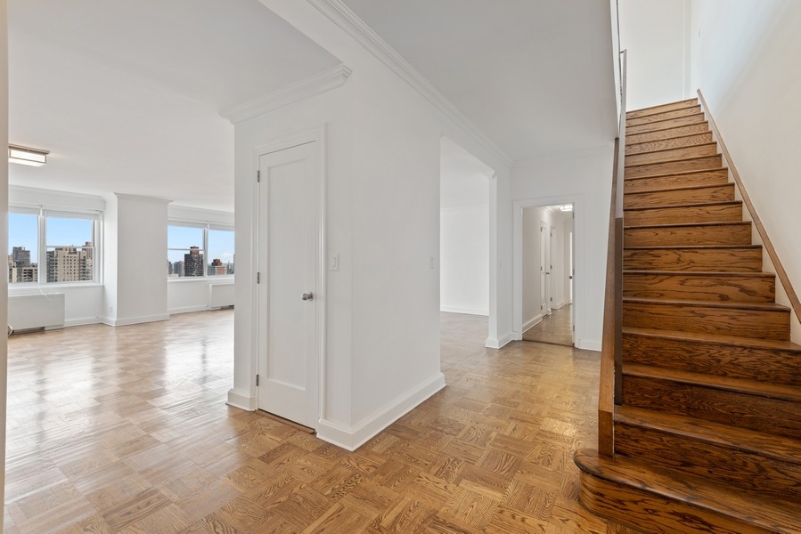 215 East 68th Street, Unit 33C Manhattan, NY 10065 - Photo 1 of 1 a view of a livingroom with wooden floor and stairs
