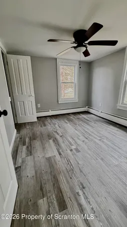 an empty room with wooden floor cabinet and windows
