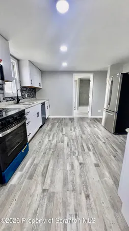 a large white kitchen with sink and stainless steel appliances