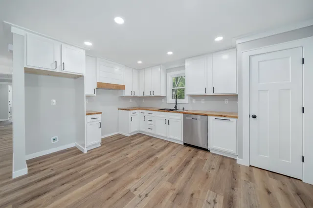 a kitchen with stainless steel appliances granite countertop a stove a sink dishwasher and a refrigerator with wooden floors