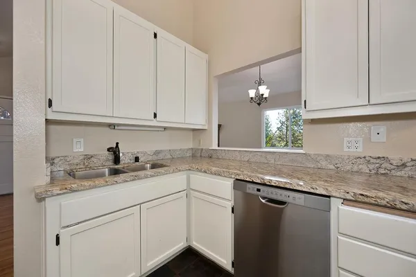 a kitchen with a sink dishwasher and white cabinets