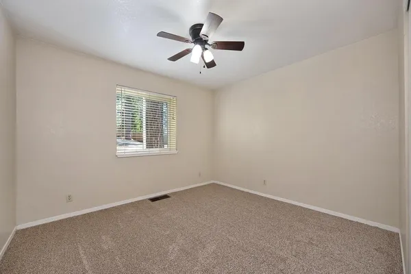 an empty room with ceiling fan and windows