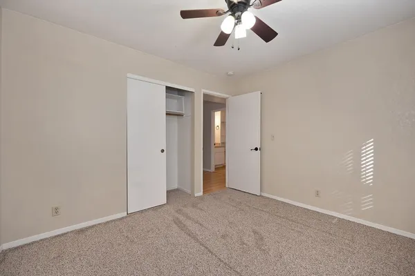 a view of an empty room with a chandelier fan