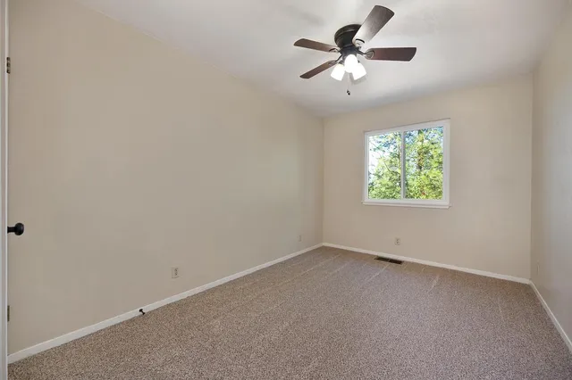 an empty room with windows and fan